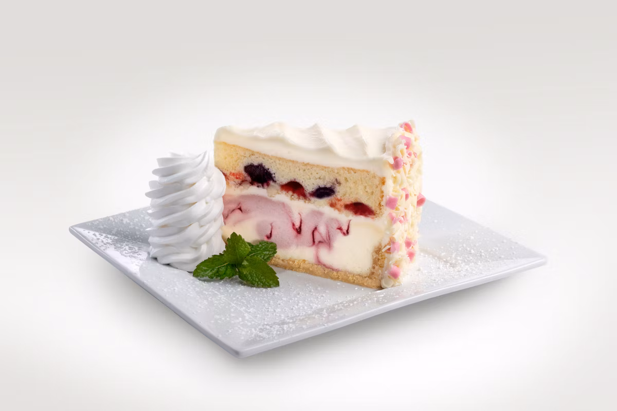 A vibrant Triple Berry Bliss Cheesecake from Cheesecake Factory, featuring layers of creamy cheesecake, fresh berry topping, and a golden crust, garnished with whipped cream.